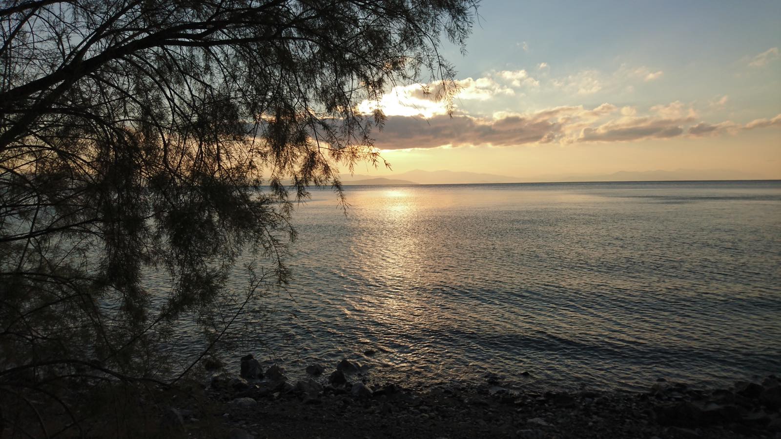 Ο ήλιος ρίχνει το τελευταίο του χάδι στα νερά, ντύνοντας τη Λίμνη με χρυσές ανταύγειες.